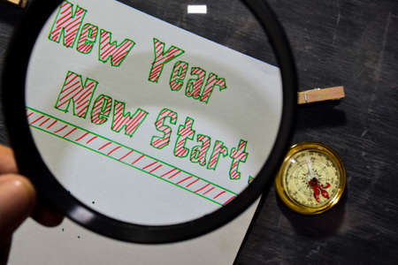 New Year New Start handwritten text on the paper with marker, compass and use magnifying glass on blackboard background. Inspiration, education and celebration conceptsの写真素材