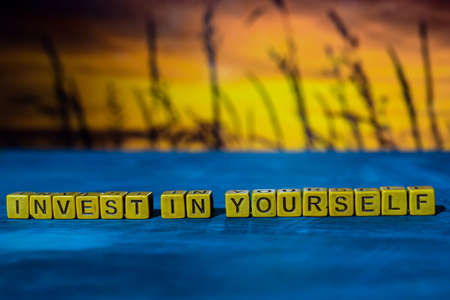 Invest in yourself on wooden blocks. Cross processed image with bokeh backgroundの写真素材