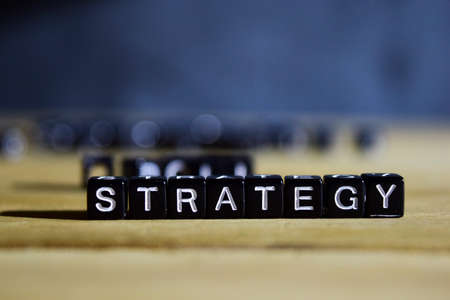 STRATEGY concept wooden blocks on the table. With personal development and motivation concept on blurred or black backgroundの写真素材