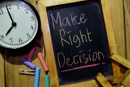 Make Right Decision on phrase colorful handwritten on chalkboard and alarm clock with motivation, inspiration and education concepts. Table backgroundの写真素材