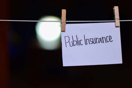 public insurance handwriting on paper. hanged with a clothes clips, medical and education concept. light blur backgroundの写真素材