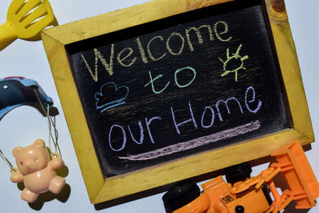 Welcome to Our Home on phrase colorful handwritten on blackboard with bear in parachute,loader and fork, white background. Education conceptの写真素材