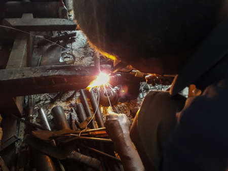 Editorial use only; An old welder in a blue T-shirt use sunglasses. Selective focus on firework....