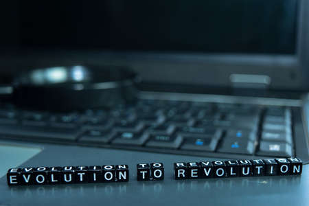 Evolution to Revolution text wooden blocks in laptop background. Business and technology concept