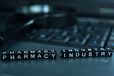 Pharmacy Industry text wooden blocks in laptop background. Business and technology concept