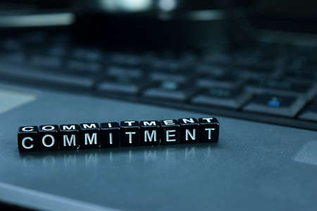 Commitment text wooden blocks in laptop background. Business and technology concept