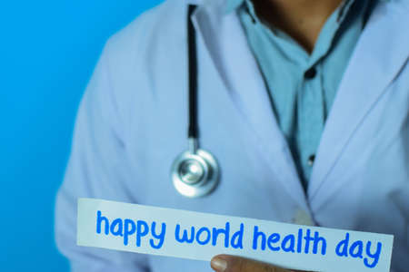 Doctor holding a card with text happy world health day. Medical and healthcare concept.の写真素材