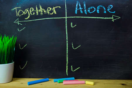 Together or Alone written with color chalk concept on the blackboardの写真素材