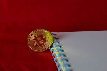 Coin bitcoin and a notebook isolated on red background, extraction of crypto currencyの写真素材