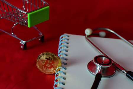Coin bitcoin,shopping cart, notebook,stethoscope and a magnifying glass isolated on red background,...