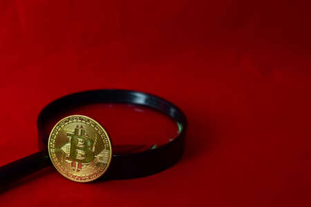 Coin bitcoin and a magnifying glass isolated on red background, extraction of crypto currencyの写真素材