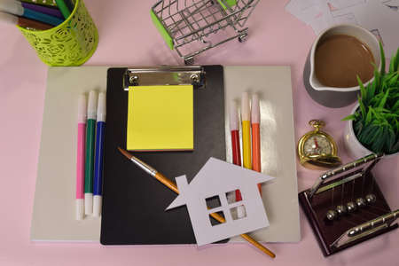 Top view of the cutting paper or drawing house on a pink table, preparing to do homework in a clipboard. Drawing Working Desk Conceptの写真素材