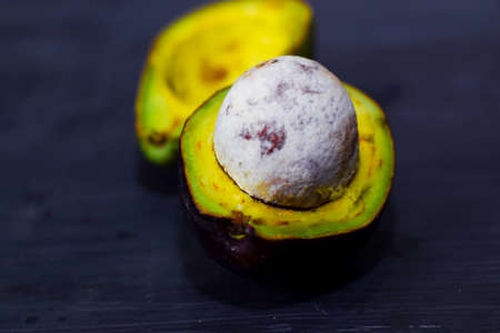 Close up fresh organic avocado halves on old black table background. Healthy food conceptの写真素材