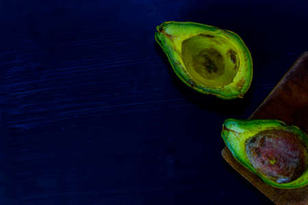 Close up fresh organic avocado halves on old black table background. Healthy food conceptの写真素材