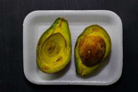 Close up fresh organic avocado halves on old black table background. Healthy food conceptの写真素材