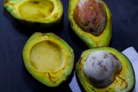 Close up fresh organic avocado halves on old black table background. Healthy food conceptの写真素材
