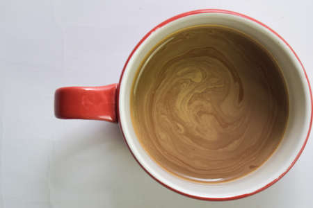 Close up hot cappuccino coffee in a red cup isolated on a white background. Selective focus on cappuccino coffeeの写真素材