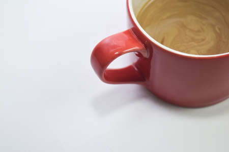 Close up hot cappuccino coffee in a red cup isolated on a white backgroundの写真素材