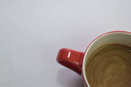 Close up hot cappuccino coffee in a red cup isolated on a white backgroundの写真素材