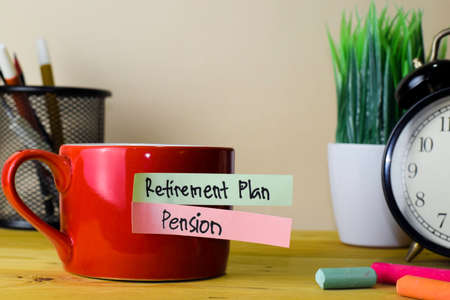 Retirement Plan and Pension. Handwriting on sticky notes in clothes pegs on wooden office deskの写真素材