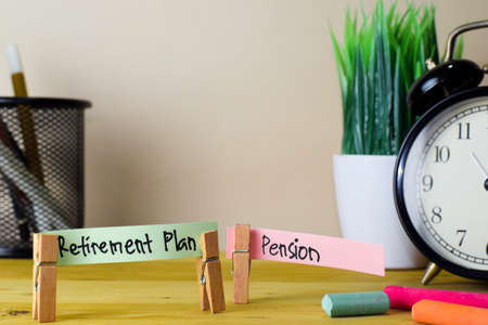 Retirement Plan and Pension. Handwriting on sticky notes in clothes pegs on wooden office deskの写真素材