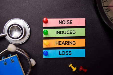 Noise Induced Hearing Loss text on Sticky Notes. Top view isolated on black background....