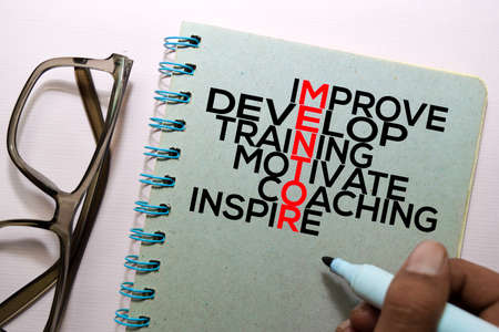 Improve, Develop, Training, Motivate, Coaching, Inspire (MENTOR) text on the book isolated on office deskの写真素材