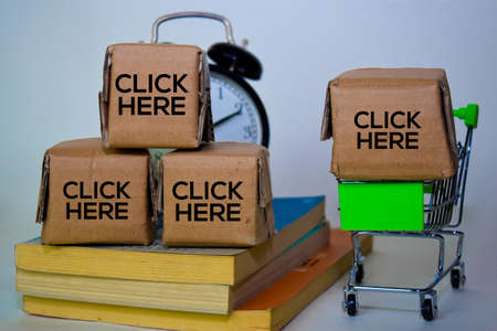 Click Here Text in small boxes and shopping cart. Concepts about online shopping. Isolated on white...