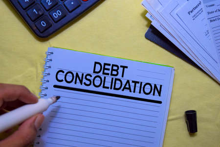 Debt Consolidation text on a book isolated on office desk.の写真素材