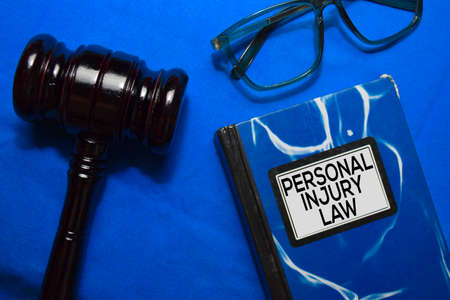 Personal Injury Law text on Book and gavel isolated on office desk.