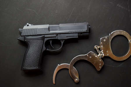 Handcuffs and Gun isolated on black background. Justice and law conceptの写真素材