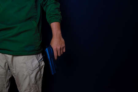 asian man holds a gun. Gun in his hand isolated on black background.