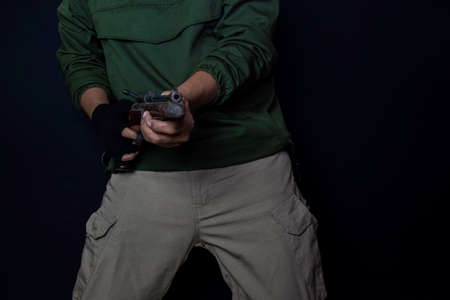 asian man holds a gun. Gun in his hand. Killed shooting his target isolated on black background.