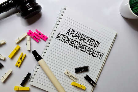 A Plan Backed By Action Becomes Reality! text on a book at office desk. Motivation concept