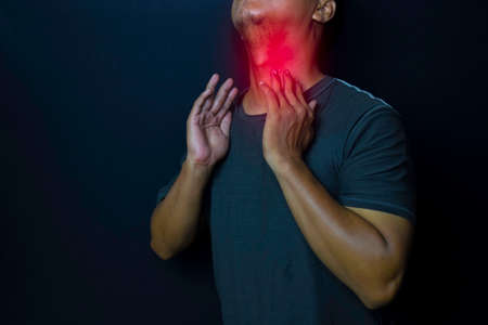 Young man thyroid gland by himself with red spot on black background. Medical or Healthcare concept
