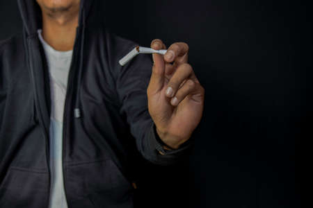 Asian Man Holding cigarettes. He feels pain on his heart with black background. Stop smoking or...