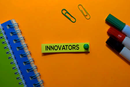 Innovators write on sticky notes. Isolated on orange table backgroundの写真素材