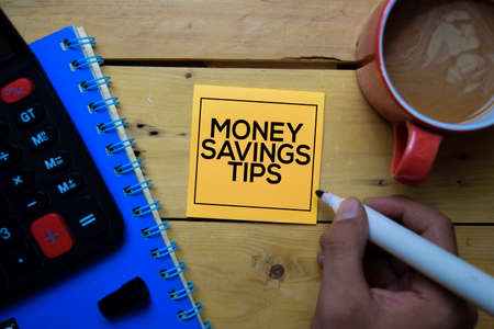 Money Savings Tips write on sticky note with wooden table backgroundの写真素材