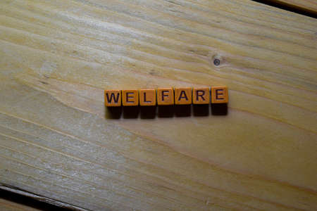 Welfare word on wooden blocks isolated on wooden tableの写真素材
