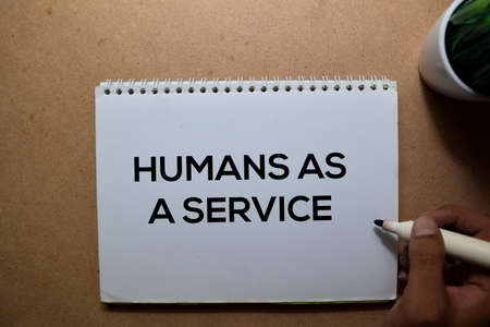 Humans As A Service write on a book. Isolated on Wooden Table