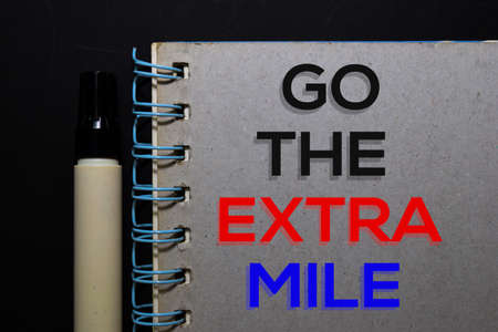 Go The Extra Mile write on book. Top view isolated on black background.の写真素材