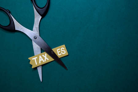 Taxes write on stick note and scissors isolated on Office Desk.の写真素材