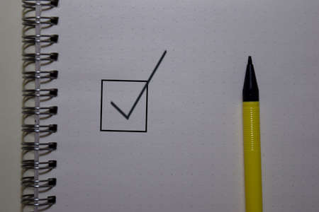 Close up the checkbox and a pen on white bookの写真素材
