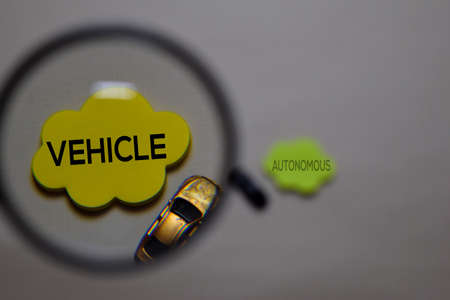 Vehicle or Autonomous write on a sticky note isolated on office desk. Selective focus on Vehicle...