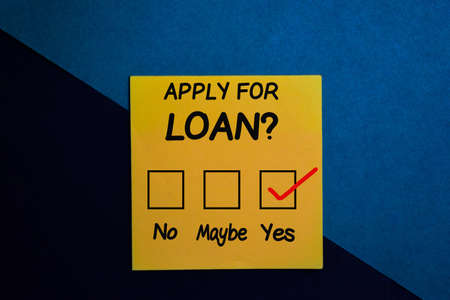 Apply for loan? and check mark write on a sticky note isolated on Office Deskの写真素材