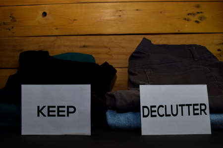 Keep and Declutter write on a sticky note between fashion clothes folded and stack isolated on...