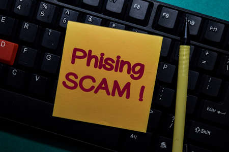 Phising Scam! write on a sticky note isolated on Office Deskの写真素材