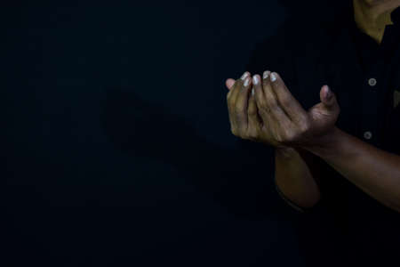 Half length view prayer of muslim Asian man. Islamic praying concept on black background. Selective focus on fingerの写真素材