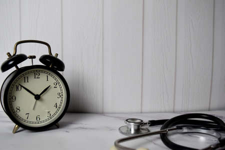 Alarm clock and stethoscope on office deskの写真素材