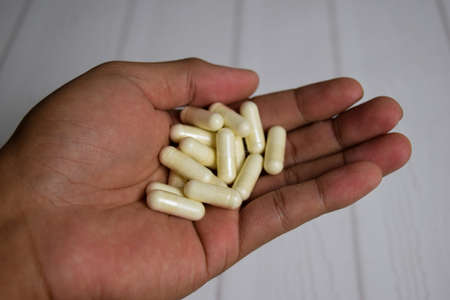 A man holding many capsules with his palm. Medical or healthcare conceptの写真素材